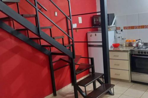 a kitchen with a red wall and a spiral staircase at Dpto económico para tres en Ballester con TV in Villa Ballester