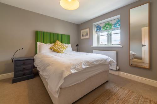 a bedroom with a bed with a green headboard and a window at Sea Pie in Burnham Market