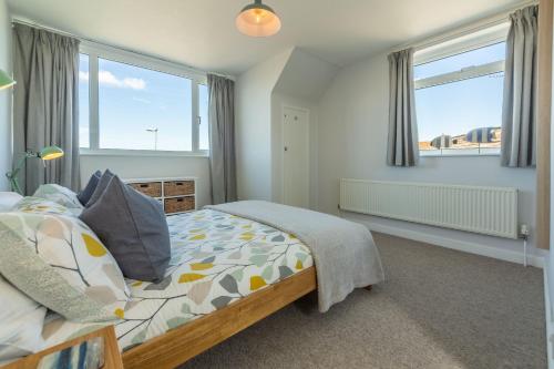 a bedroom with a bed and two windows at High View in Wells next the Sea