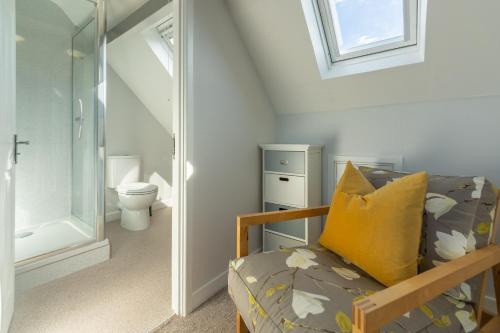 a bathroom with a toilet and a couch with a yellow pillow at High View in Wells next the Sea