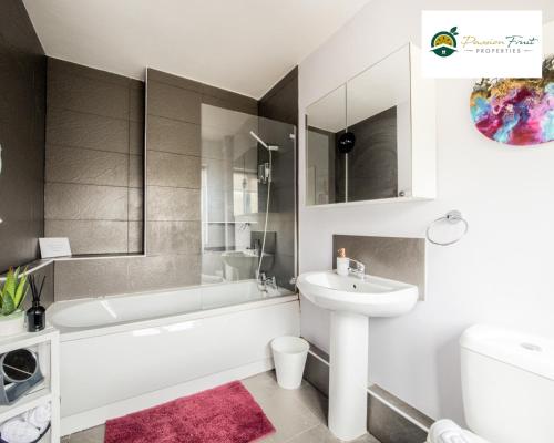 La salle de bains est pourvue d'une baignoire blanche et d'un lavabo. dans l'établissement 3 BedRoom House with 5 Beds House By Passionfruit Properties Near Coventry City Centre - BCC, à Coventry