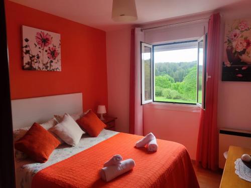Dormitorio rojo con cama y ventana en Apartamentos turísticos Lemos en Pedrouzo