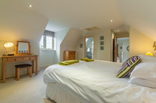 a bedroom with a large white bed and a desk at Kittiwake Cottage in Brancaster