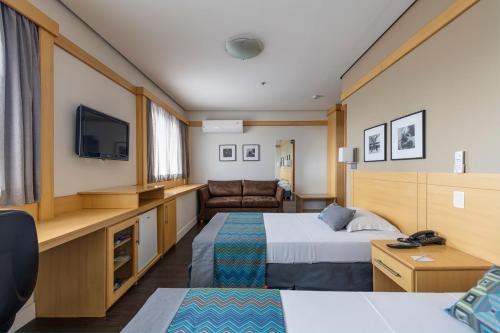 a hotel room with two beds and a tv at Monreale Plus Guarulhos International Airport in Guarulhos