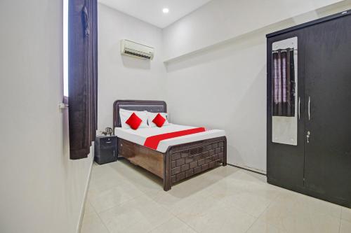 ein Schlafzimmer mit einem Bett mit roten Kissen in der Unterkunft Flagship Crossroad Rooms in Nagpur
