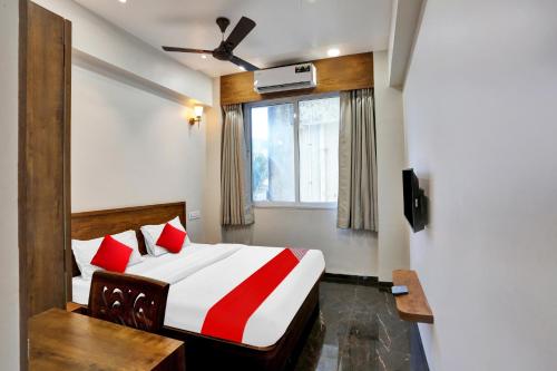um quarto com uma cama com almofadas vermelhas e uma janela em Capital O Hotel Calista em Mumbai