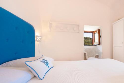a bedroom with a white bed with a blue headboard at Torre Turbolo Apartments in Massa Lubrense