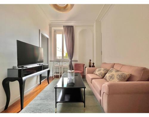 a living room with a couch and a flat screen tv at Le Nid de Papillons Appartement Haut de gamme Dijon Centre in Dijon