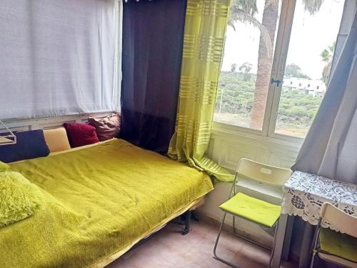 a bedroom with a yellow bed and a window at Cozy studio in Costa del Silencio in the south coast of Tenerife in Costa Del Silencio