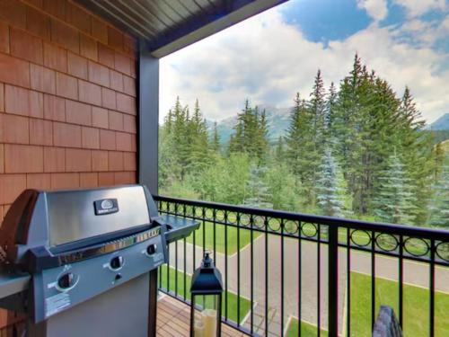 a grill on a balcony with a view of the mountains at The Mountaineer by InstantSuites Pool & HotTub in Canmore