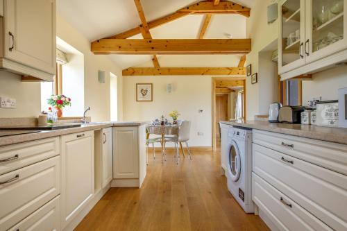 a kitchen with white cabinets and a washer and dryer at Princes Barn in Neatishead
