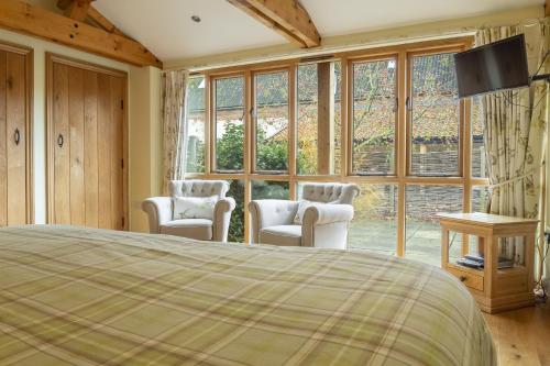 a bedroom with a bed and chairs and a large window at Princes Barn in Neatishead