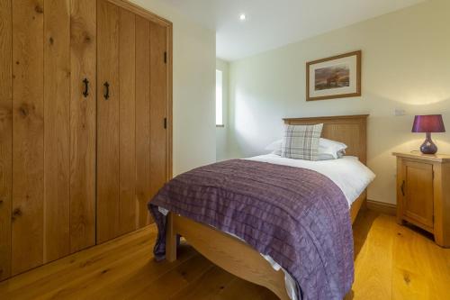 a bedroom with a large bed with a purple blanket at Princes Barn in Neatishead