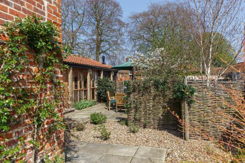 a garden with a brick building and a fence at Princes Barn in Neatishead
