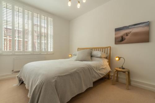 a white bedroom with a bed and two windows at Seahorses in Brancaster