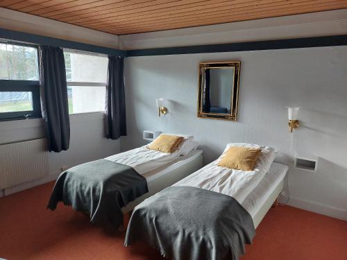 2 Betten in einem Zimmer mit Spiegel und Fenstern in der Unterkunft Øiseth Hotell AS in Rendalen