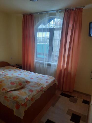 Schlafzimmer mit einem Bett und einem Fenster mit rosa Vorhängen in der Unterkunft Casa Crivimex in Azuga