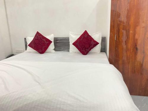 a bed with two red pillows on top of it at OYO Hotel Mahima in Pānīpat