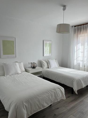2 camas en una habitación con paredes blancas en Casa Batea, en Moaña