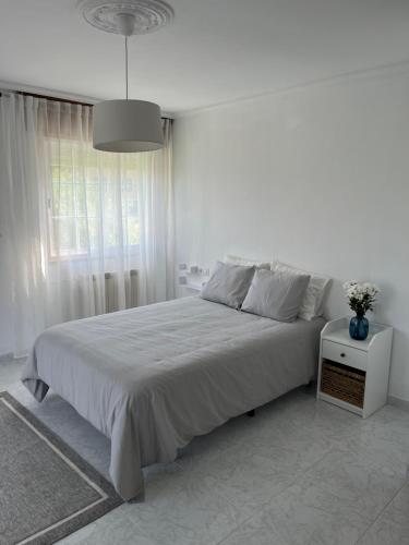 Un dormitorio blanco con una cama grande y una ventana en Casa Batea, en Moaña