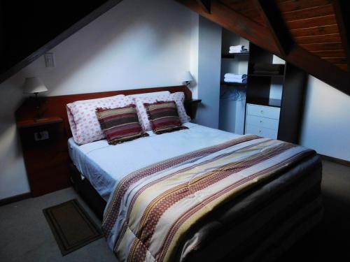 1 dormitorio con 1 cama grande y 2 almohadas en Ikalum Apart en El Calafate