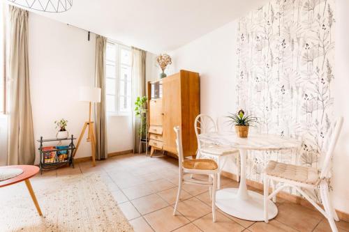 un salon avec une table et des chaises blanches dans l'établissement Coquet appartement typique du Panier, à Marseille
