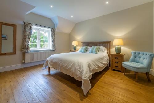 a bedroom with a bed and a blue chair at 1 Hall Lane Cottages in Thornham