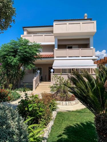 a large white house with stairs and plants at Haus Lupić in Rab