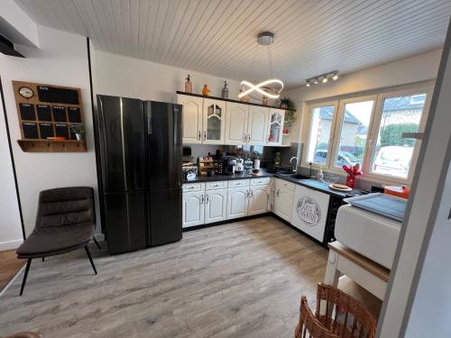 a kitchen with a black refrigerator and white cabinets at La suite du Theatre in Bourges