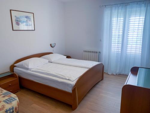 a bedroom with a large bed with white sheets at Haus Lupić in Rab