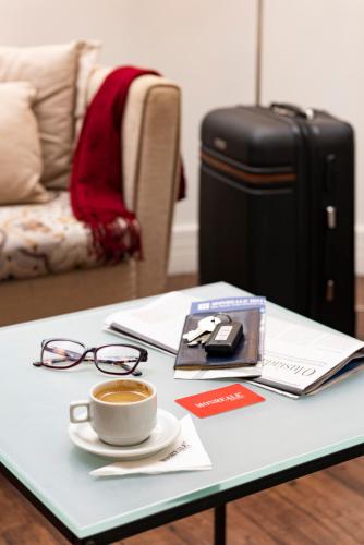 a table with a cup of coffee and a suitcase at Monreale Plus Guarulhos International Airport in Guarulhos