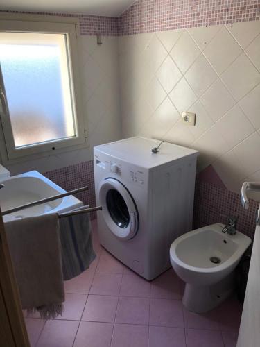 a bathroom with a washing machine and a toilet at Mansarda mentana in Vittoria