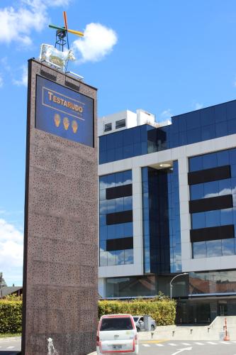 una torre de reloj frente a un edificio con una señal en Hotel Sabana Park, en Cajicá