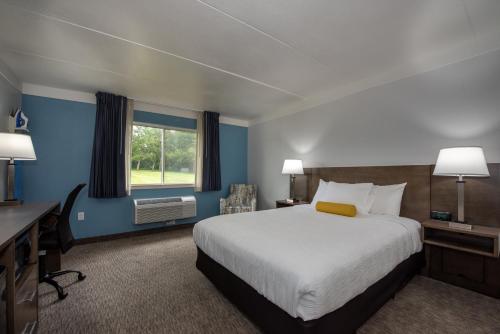 a hotel room with a bed and a desk and a window at Hotel Pommier Indianola in Indianola