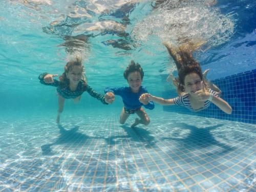three children playing in the water in a swimming pool at Serrambi Resort in Porto De Galinhas