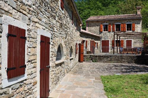un edificio de piedra con puertas rojas y un camino de piedra en Casa Cocola, en Cerovlje