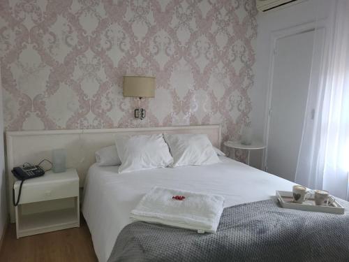 a bedroom with a white bed and a wall at HOTEL LOS ARENALES DE JERTE in Jerte