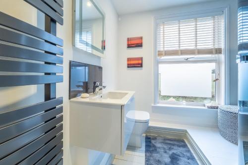 a bathroom with a sink and a toilet and a window at Brook House in Briston