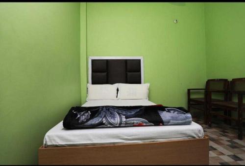 uma cama num quarto com uma parede verde em Hotel O POP Hotel Amrit Castle em Moradabad