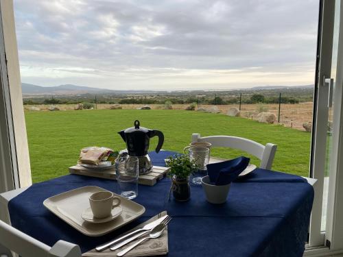 a table with a blue table cloth and a view of a field at Is Arenas Biancas Agriturismo in Teulada
