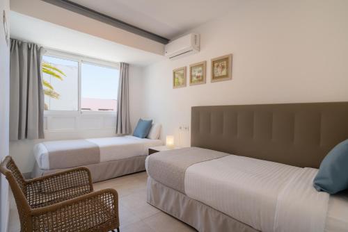 a hotel room with two beds and a window at Sabbia Suites Noa Boutique Apartments in Puerto del Carmen