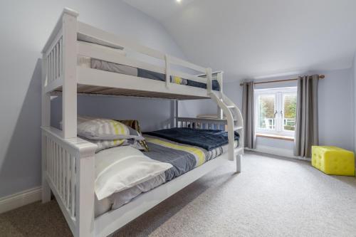 a white bunk bed in a room with a window at Greyhound Cottage in Sculthorpe