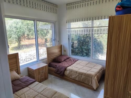 ein Schlafzimmer mit einem Bett und einem großen Fenster in der Unterkunft Chalets in the middle of Ajloun forests شاليه و مزرعة في وسط غابات عجلون in Adschlun