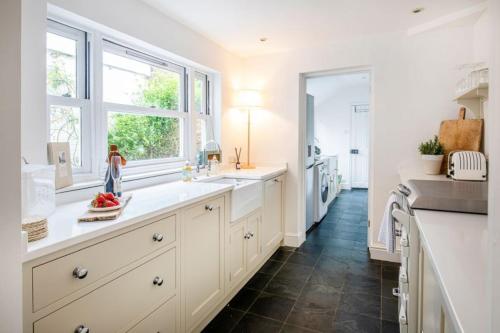a white kitchen with a sink and a window at Tide Cottage O in Overstrand