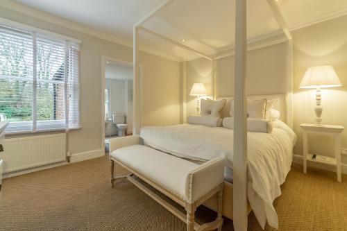 a bedroom with a white bed and a chair at Tide Cottage O in Overstrand