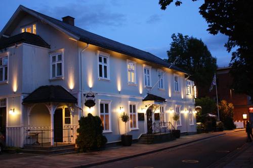 a white building with lights on a street at Reenskaug Hotel in Drøbak