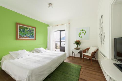 a bedroom with a white bed and a green wall at Art Hotel Ristorante Posta Al Lago in Ronco sopra Ascona