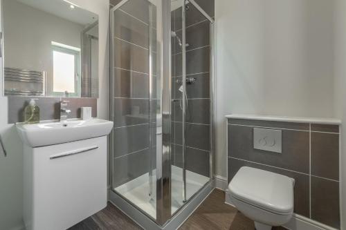 a bathroom with a shower and a toilet and a sink at Samphire House in Bodham