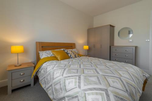 a bedroom with a bed and a dresser and lamps at Samphire House in Bodham
