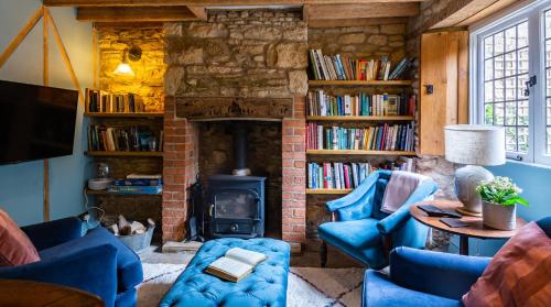 a living room with a brick fireplace and blue chairs at Cedar Cottage in Chipping Norton